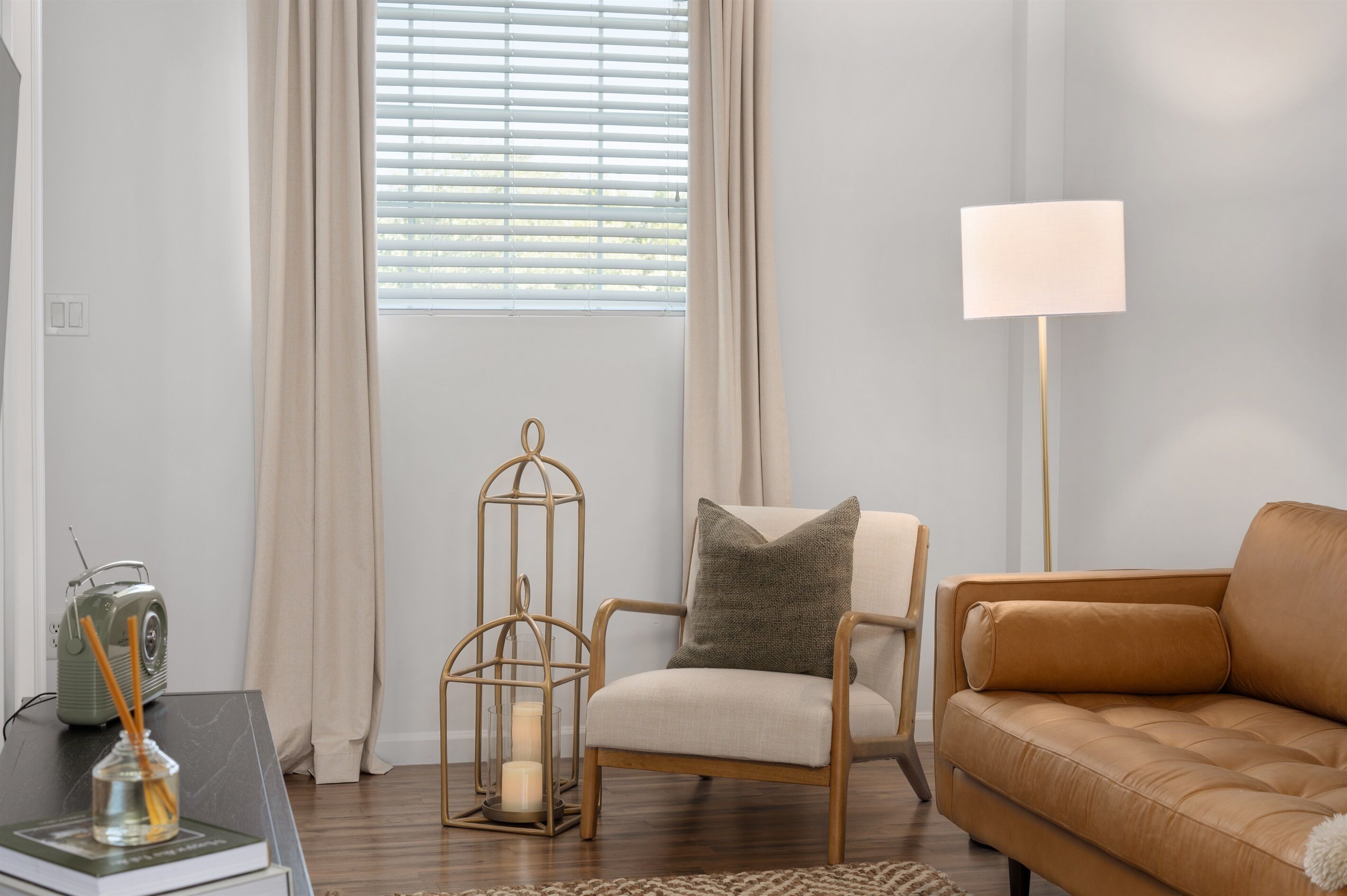 A living room with a sofa, a chair, a floor lamp, a decorative lantern, and a vintage radio.