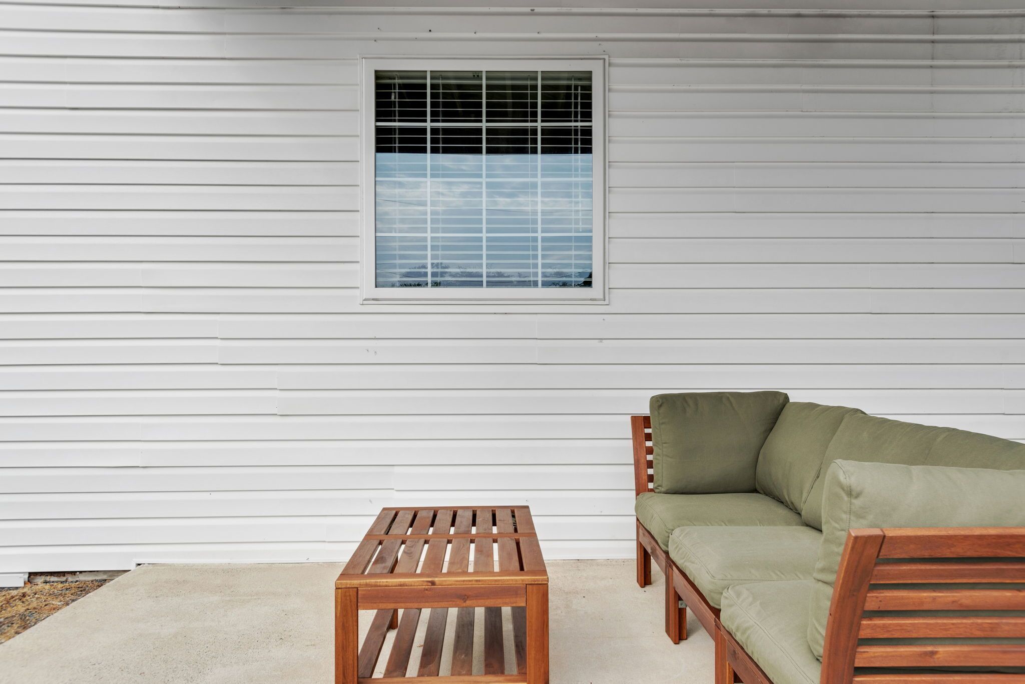 A room with a wooden bench, a green sofa, and a window with blinds.
