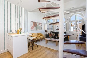 A modern interior with a kitchen island, seating area, and a staircase.