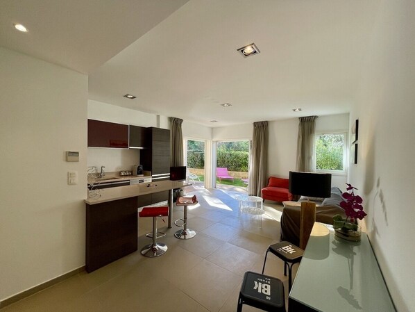 A modern kitchen with a dining area, a TV, and a view of the garden.