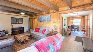 A cozy wooden interior with a sofa, coffee table, and a dining area. - Hot Tub! Secluded Cabin, overlook Lake Pagosa on 39 acres, No Neighbors! (Pagosa Springs)