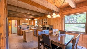 A spacious kitchen with wooden cabinets, a central island, and pendant lighting. - Hot Tub! Secluded Cabin, overlook Lake Pagosa on 39 acres, No Neighbors! (Pagosa Springs)