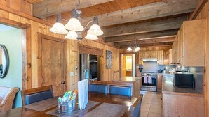 A wooden interior with a dining area, kitchen, and a large wooden door. - Hot Tub! Secluded Cabin, overlook Lake Pagosa on 39 acres, No Neighbors! (Pagosa Springs)