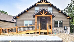 A two-story building with a wooden facade, a stone accent wall, and a front porch with a wooden railing.
