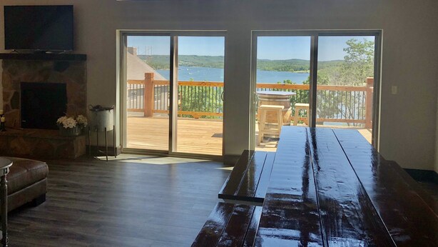 A spacious room with a large sliding glass door leading to an outdoor deck with a view of a lake.