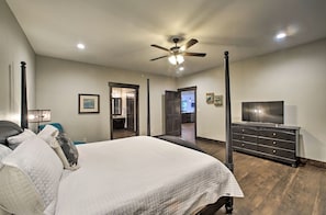 A bedroom with a bed, a dresser, a TV, and a ceiling fan.