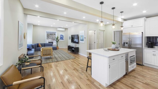 A spacious living area with a sofa, coffee table, and a dining area with a kitchen island.