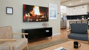 A living room with a fireplace, a dining area, and a kitchen.