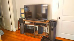 A home office setup with a TV, computer, and speakers on a wooden desk. - Urban Retreat on Flint in the Heart of Jonesboro (Jonesboro)