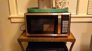 A compact kitchen setup with a microwave, a coffee maker, and a small refrigerator on a wooden table. - Urban Retreat on Flint in the Heart of Jonesboro (Jonesboro)