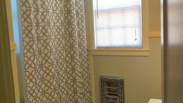 Een bad/douchecombinatie, een haardroger, handdoeken, zeep