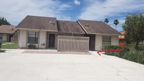 Une maison à deux étages avec un garage donnant sur la façade, un petit porche et une pelouse bien entretenue.