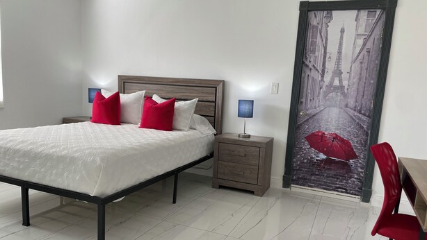 Une chambre à coucher avec un lit, des tables de chevet, un bureau et une chaise.
