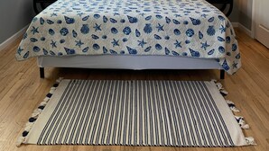 Un dormitorio con una cama, dos mesitas de noche, un ventilador de techo y dos lámparas de pared.