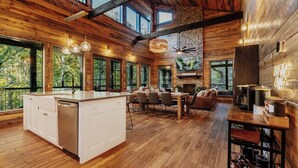 Une cuisine spacieuse dotée d’un grand îlot central, de planchers en bois et de grandes fenêtres offrant une vue sur l’extérieur.