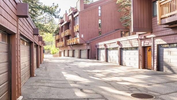 A row of red wooden buildings with multiple garage doors, likely part of a residential complex. - Nice condo in a resort like complex with Mtn views, pool and tennis! (Mammoth Lakes)