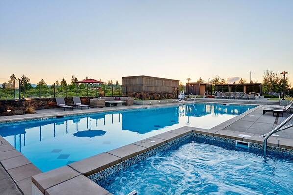 A swimming pool with lounge chairs and a covered seating area.
