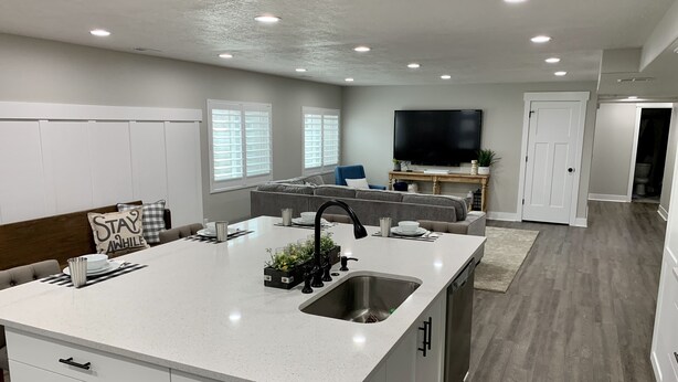 A modern kitchen with a central island, white cabinetry, and a built-in sink. - Location, comfort and cleanliness.<br>Whole basement 1600-plus square feet.  (LEHI CITY)