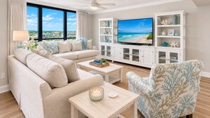Una sala de estar con sofá, sillón, mesa de centro y televisor.