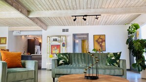 A modern living room with a green sofa, a round wooden coffee table, and a black and white checkered rug. - Paloma House - Mid century style with Frida Kahlo Soul (Palm Springs)