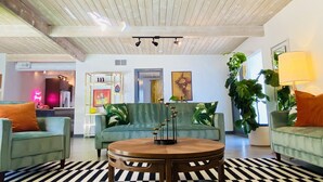 A spacious living area with a wooden ceiling, a round wooden table, and two green sofas with orange cushions. - Paloma House - Mid century style with Frida Kahlo Soul (Palm Springs)