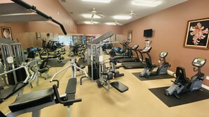Een fitnessruimte met diverse trainingsapparaten, waaronder loopbanden, hometrainers en krachtapparaten.