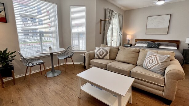 Een moderne woonkamer met een beige bank, een witte salontafel en een ronde eettafel met stoelen.