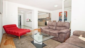 A modern living room with a glass coffee table, red and brown sofas, and a kitchen in the background. - ESMA 2 - Deluxe Apartment (Rovinj)