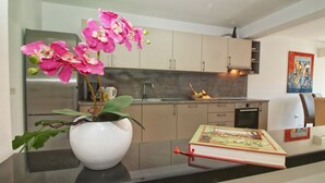 A modern kitchen with light-colored cabinets, a stainless steel refrigerator, and a vase with pink orchids on the counter. - ESMA 2 - Deluxe Apartment (Rovinj)