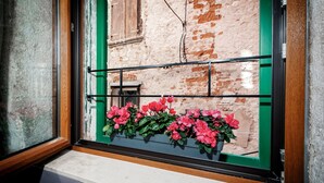 Ein Fenster mit einem Metallgitter, einer Ziegelwand und einem Holzrahmen.