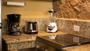 A kitchen with a coffee maker, toaster, and blender on a granite countertop.