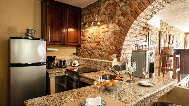 A kitchen with granite countertops, a refrigerator, a coffee maker, and a sink.