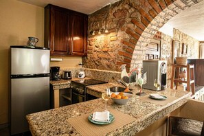 A kitchen with granite countertops, a refrigerator, a coffee maker, and a sink.