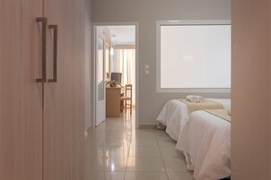 Habitación de hotel con dos camas, un escritorio con silla y un ventanal grande.