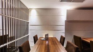 Un salón de conferencias con una mesa de madera, seis sillas y un ordenador portátil sobre la mesa.