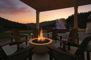 Une terrasse extérieure dotée d’un foyer, de sièges et offrant une vue sur le paysage.