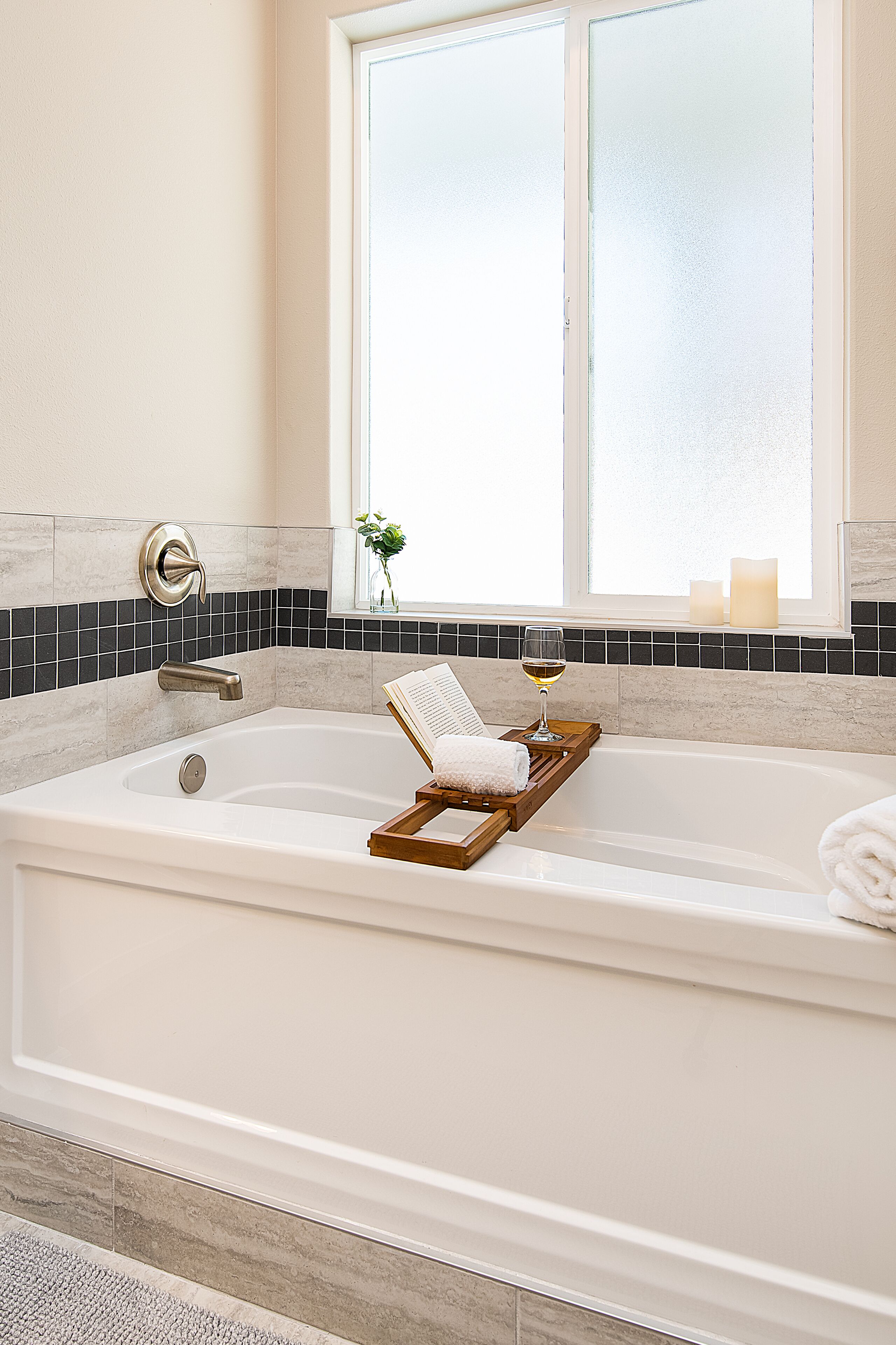 A bathroom with a large bathtub, a window, and a small plant on the windowsill.