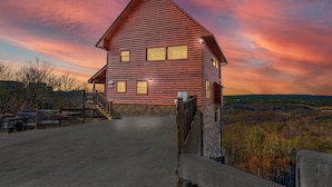 A log cabin with a stone foundation, a concrete driveway, and a scenic view of the surrounding landscape. - Specials! Stunning Views+Location. 4 King Beds w/ en suite. Hot Tub, Games! (Sevierville)