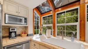 A kitchen with a built-in microwave, coffee maker, and a large window with a view of trees.