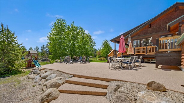 A wooden cabin with outdoor seating, a children's play area, and a clear sky.