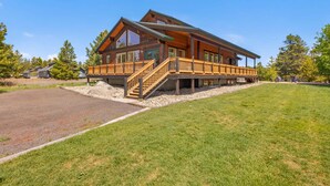 A large wooden lodge with a covered deck and a staircase leading to the entrance.