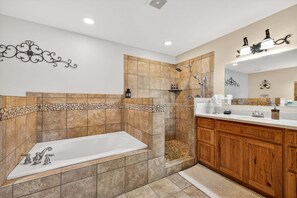 A modern bathroom with a freestanding bathtub, a shower area, wooden cabinets, and a vanity with a mirror.