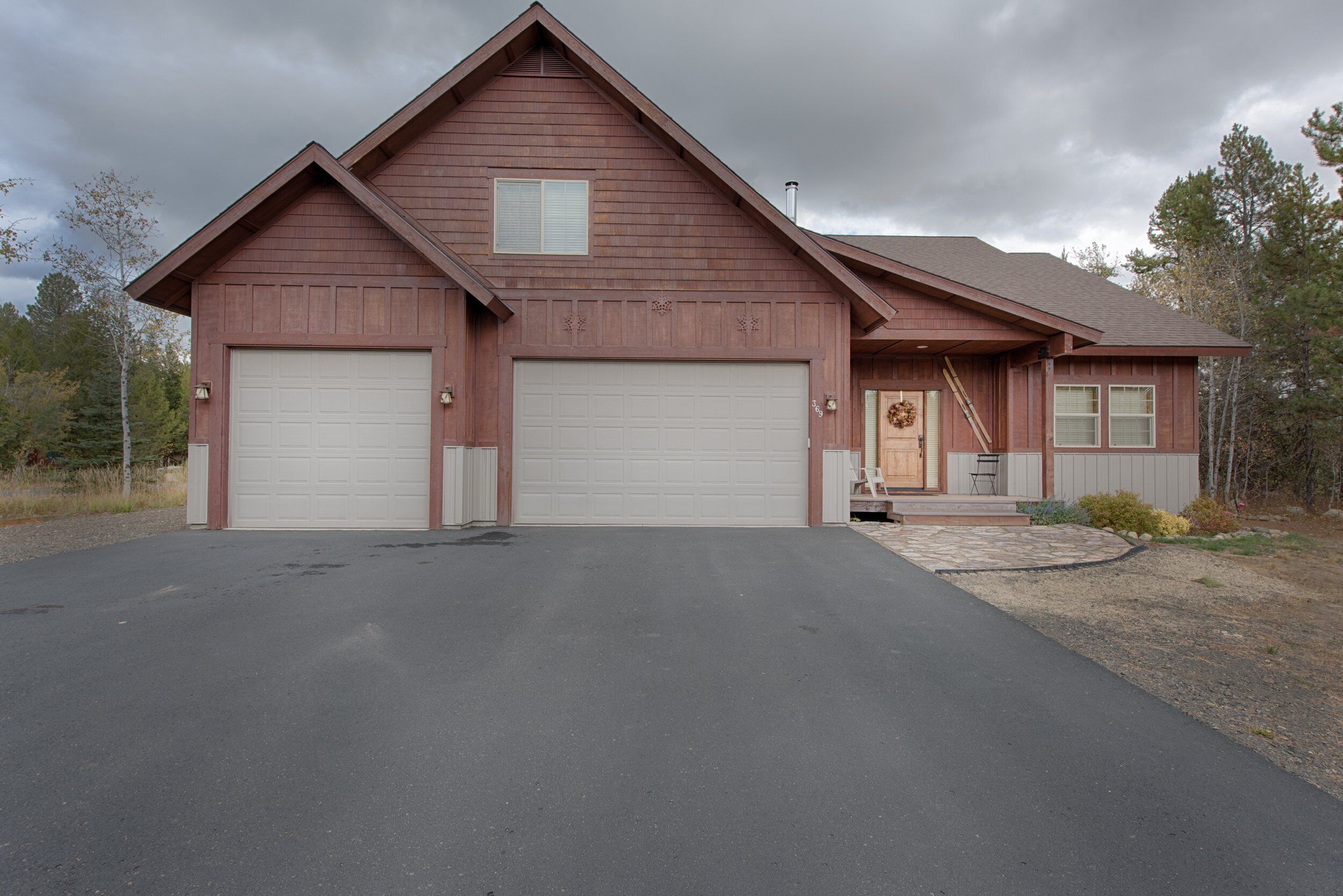 A two-story house with a garage, a front porch, and a stone pathway leading to the entrance.