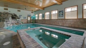 An indoor swimming pool with a wooden ceiling, stone wall, and tiled floor. - Seasons at McCall - Indoor Pool - Game Room - Outdoor Hot Tub - Bar room - Pool table (McCall)