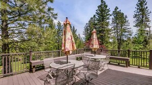 A wooden deck with outdoor furniture and umbrellas, surrounded by trees. - Seasons at McCall - Indoor Pool - Game Room - Outdoor Hot Tub - Bar room - Pool table (McCall)