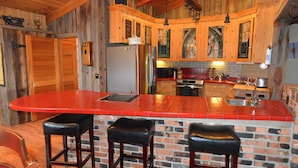 A kitchen with wooden cabinets, a red countertop, and a brick backsplash. - Seasons at McCall - Indoor Pool - Game Room - Outdoor Hot Tub - Bar room - Pool table (McCall)