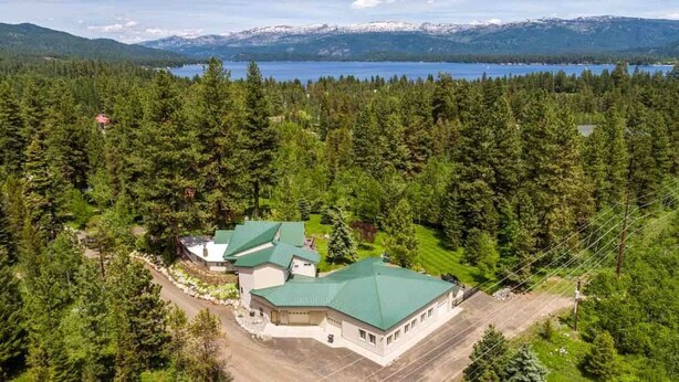 A lodge with multiple buildings surrounded by dense forest and a lake in the background. - Seasons at McCall - Indoor Pool - Game Room - Outdoor Hot Tub - Bar room - Pool table (McCall)