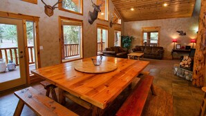Un intérieur spacieux en bois, avec une grande table à manger, des bancs et une cheminée.