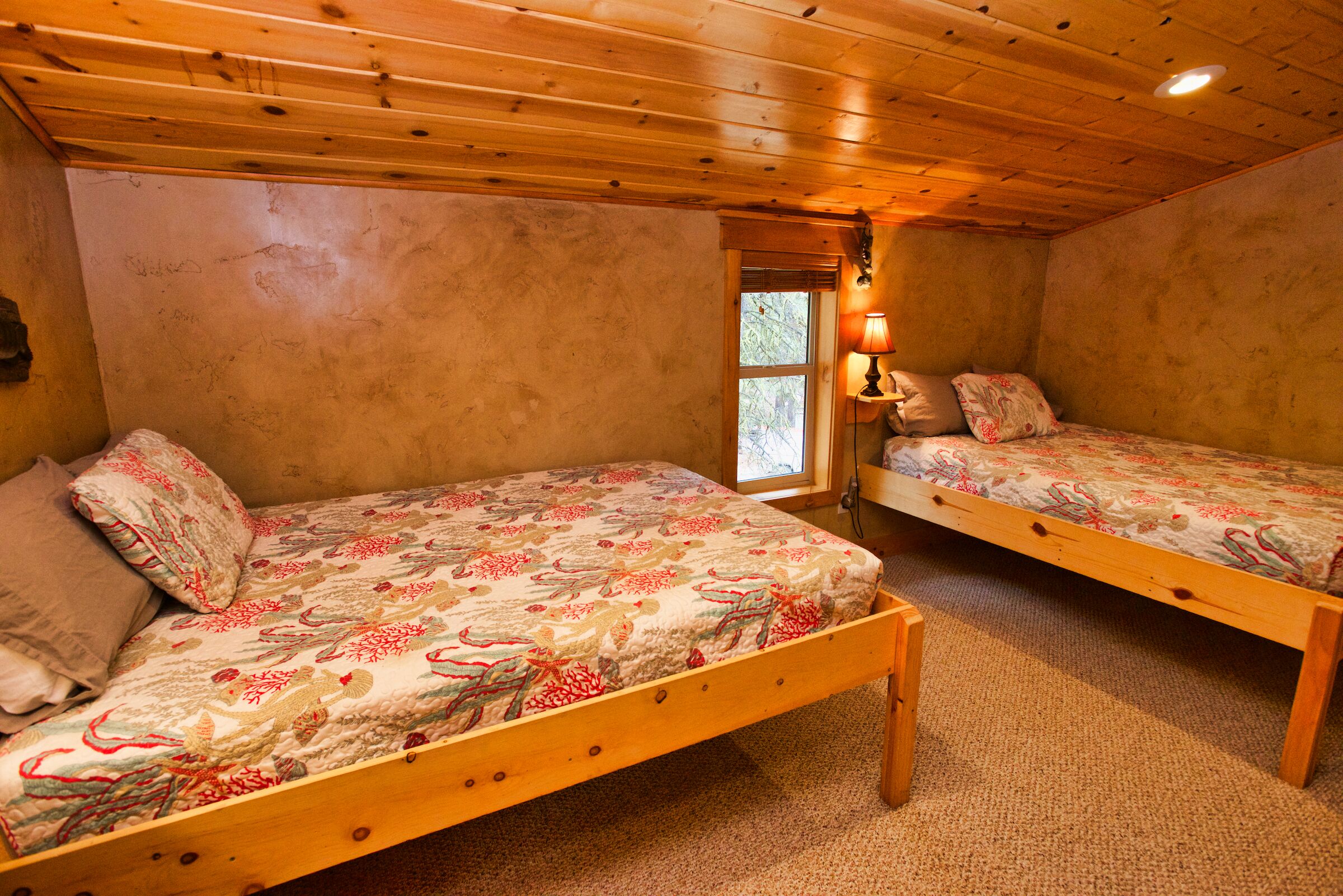 Un dormitorio con dos camas de madera, una ventana y una lámpara.