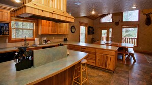 Une cuisine spacieuse avec des meubles en bois, un grand îlot central et un coin repas équipé d’une banquette.